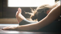Young woman in paschimottanasana pose, home interior background,