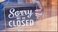Woman Holding up a shop sign saying: Sorry we're Closed