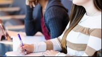 Unrecognizable female college student takes notes in class