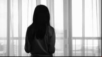 Back view image of sad lonely girl looking trough the window in black and white monochrome photo