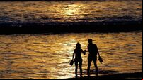 Two tourists walk along Kuta beach durin