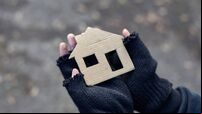 young homeless boy holding a cardboard house
