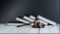 Law concept - Open law book with a wooden judges gavel on table in a courtroom or law enforcement office isolated on white backg
