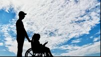 A disabled girl in a wheelchair and her dad on a walk reading a book