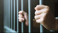Man in prison hands of behind hold Steel cage jail bars. offender criminal locked in jail.
